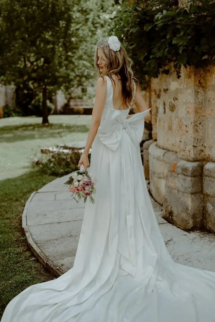 Mlada nosi beli fascinator za venčanje Rozzario - cela figura sa venčanicom